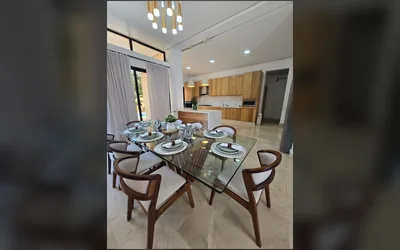 Comedor formal y cocina de madera clara en villa de Jarabacoa