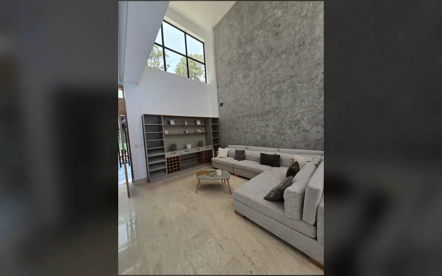 Sala principal con doble altura, ventanales y pared de acento