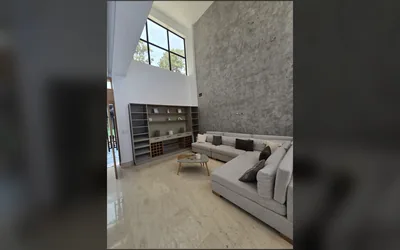 Sala principal con doble altura, ventanales y pared de acento