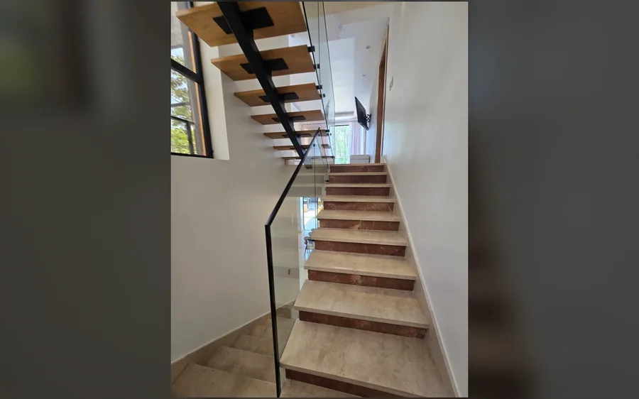 Escaleras interiores con barandas de cristal y madera