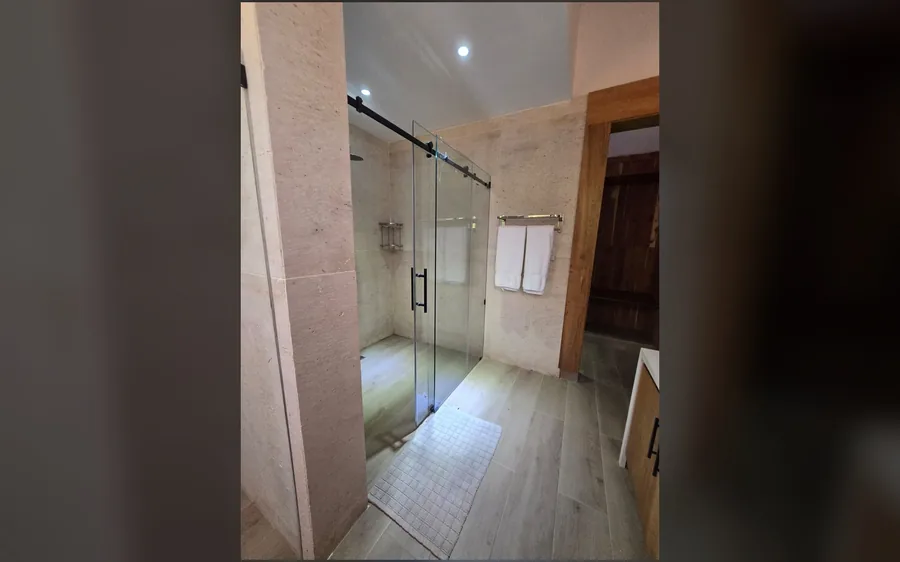 Bano con ducha en cristal, revestimiento claro y terminacion moderna