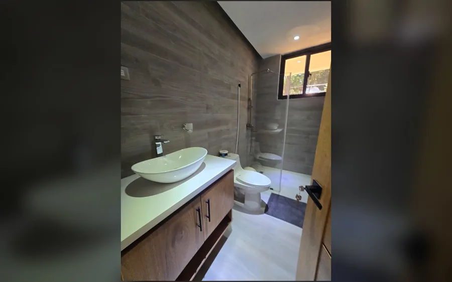 Bano con lavamanos de sobreponer y ducha en cristal