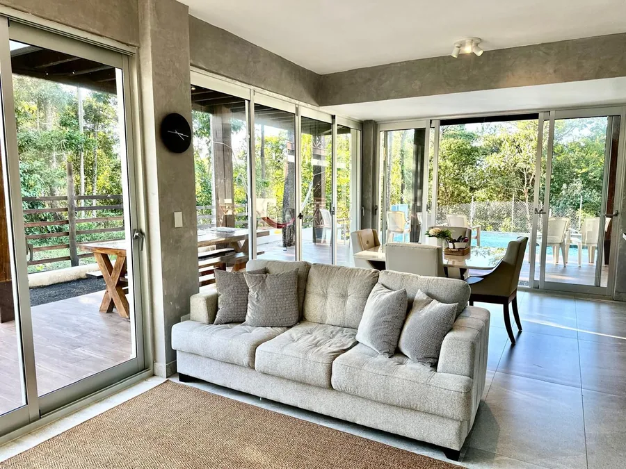 Sala y comedor con ventanales hacia terraza, piscina y areas verdes