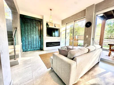 Sala de TV con sofa amplio, escalera interior y salida hacia la terraza