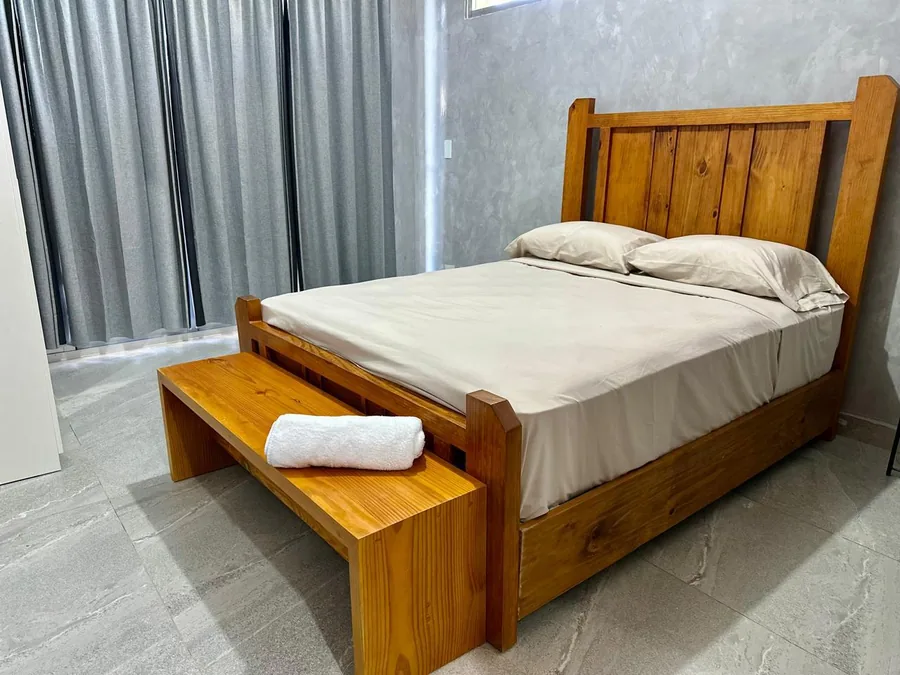 Habitacion de villa en Jarabacoa con cama y banco de madera