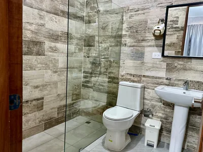 Bano con ducha en cristal, lavamanos y revestimiento moderno