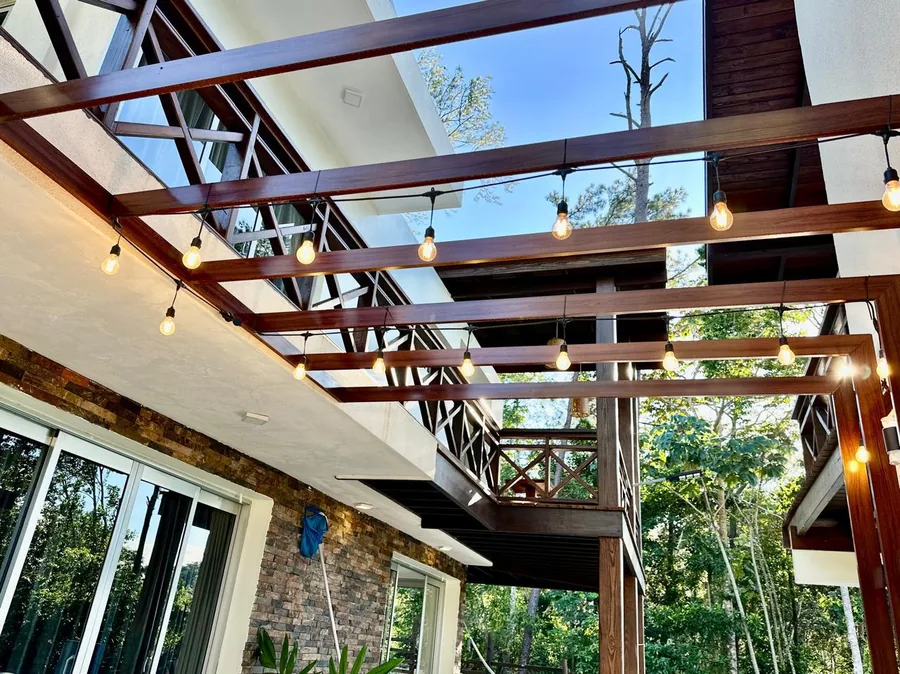 Pergola exterior con luces, balcones de madera y areas sociales