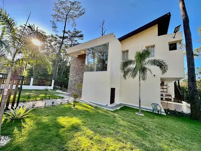 Jardin lateral con fachada de villa y arboles en Buena Vista