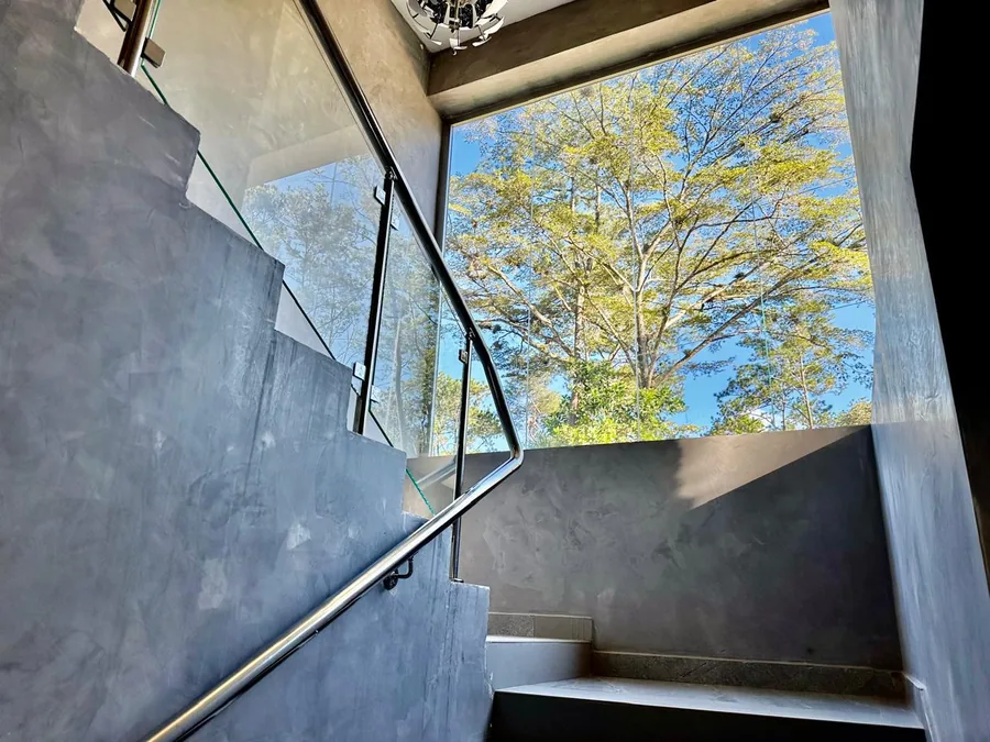 Escalera interior con baranda de cristal y vista al entorno verde