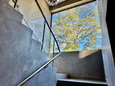 Escalera interior con baranda de cristal y vista al entorno verde