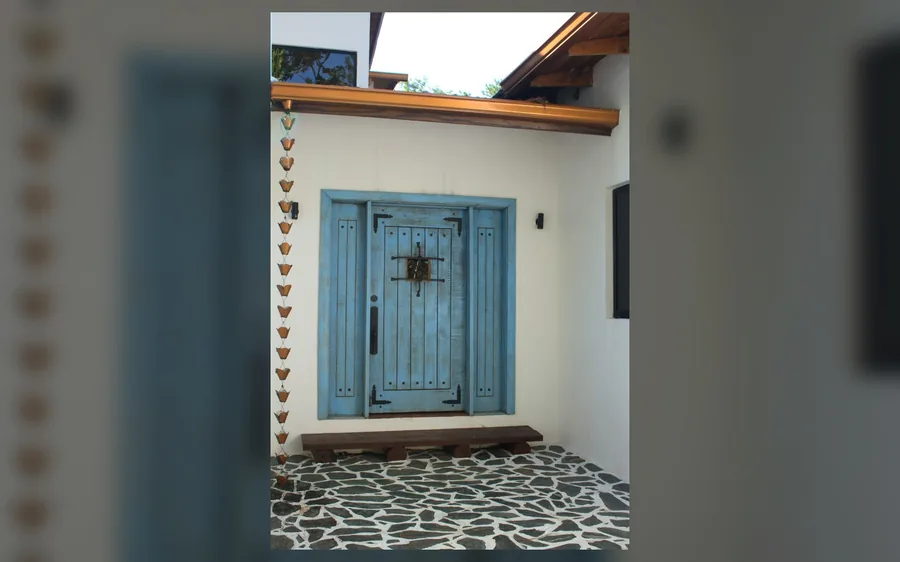 Entrada principal de villa en Jarabacoa con puerta azul y piso de piedra